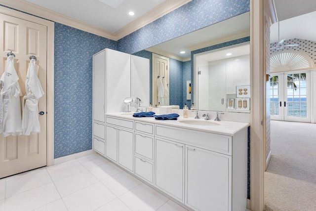 bathroom featuring crown molding, double vanity, a sink, and wallpapered walls