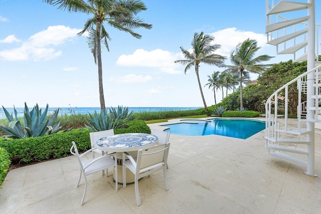 pool with a water view, stairs, and a patio