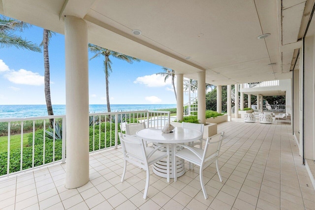 view of patio / terrace with outdoor dining area, a water view, a beach view, and stairs