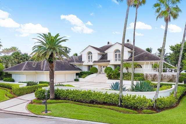 view of front of home with a garage, driveway, a balcony, and a front lawn