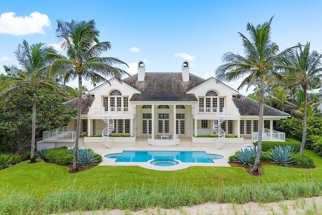 rear view of house featuring french doors, a balcony, a yard, a patio area, and a pool with connected hot tub