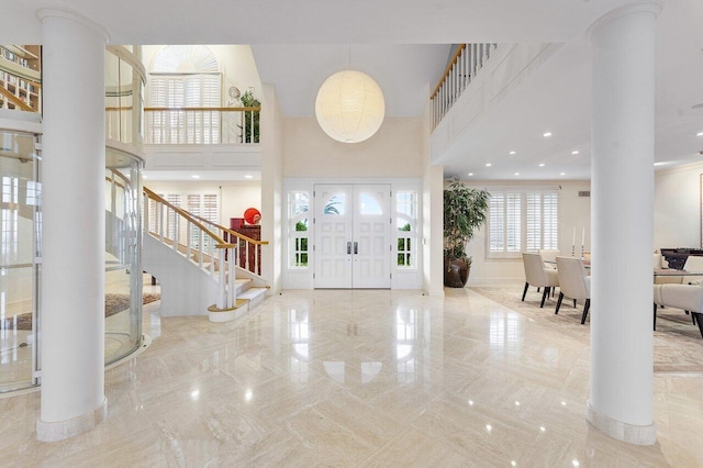 foyer entrance featuring recessed lighting, a towering ceiling, marble finish floor, stairway, and ornate columns