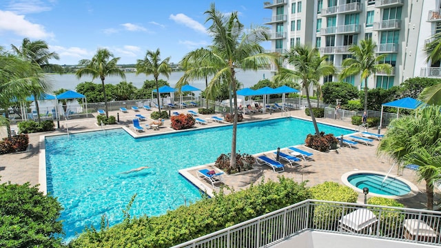 view of swimming pool featuring a patio area, a community hot tub, and a water view