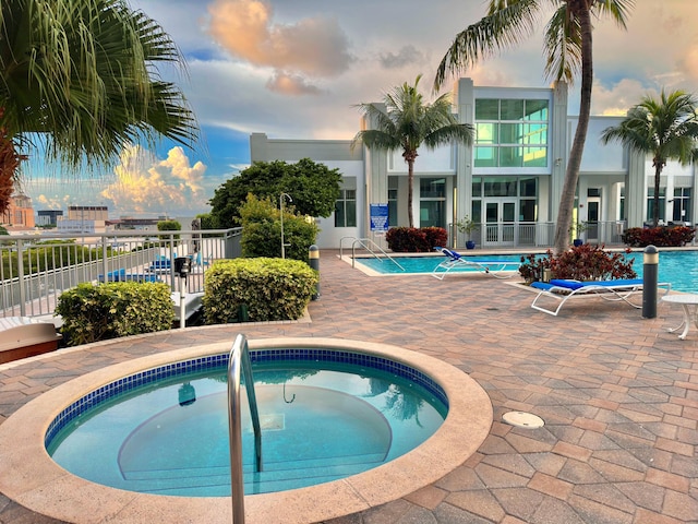 pool at dusk featuring a community hot tub