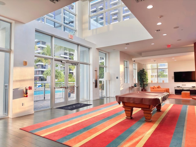 recreation room with french doors, a towering ceiling, a healthy amount of sunlight, and billiards