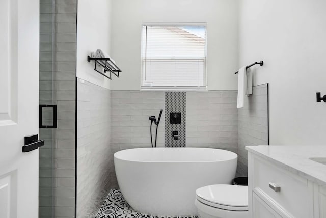 bathroom with vanity, tile walls, toilet, and a washtub