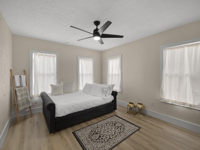 bedroom featuring light hardwood / wood-style floors, a textured ceiling, and ceiling fan