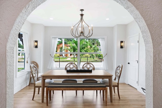 dining area with light hardwood / wood-style flooring and an inviting chandelier