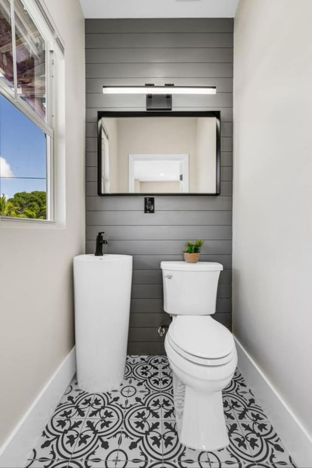 bathroom with toilet, wood walls, and tile patterned flooring