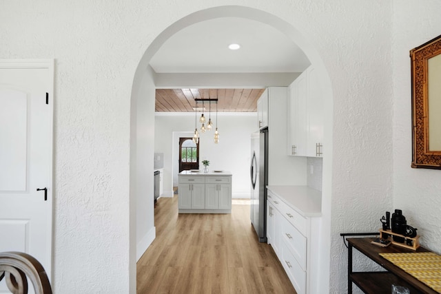 hall with light hardwood / wood-style floors, an inviting chandelier, and wooden ceiling