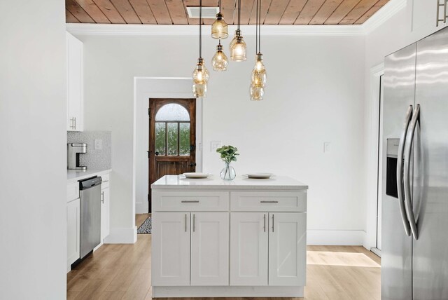 kitchen with hanging light fixtures, ornamental molding, white cabinetry, appliances with stainless steel finishes, and light hardwood / wood-style floors