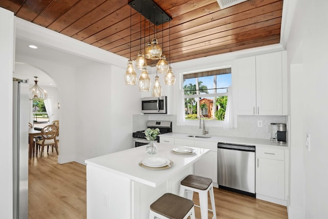 kitchen featuring wood ceiling, stainless steel appliances, decorative light fixtures, white cabinetry, and light hardwood / wood-style floors