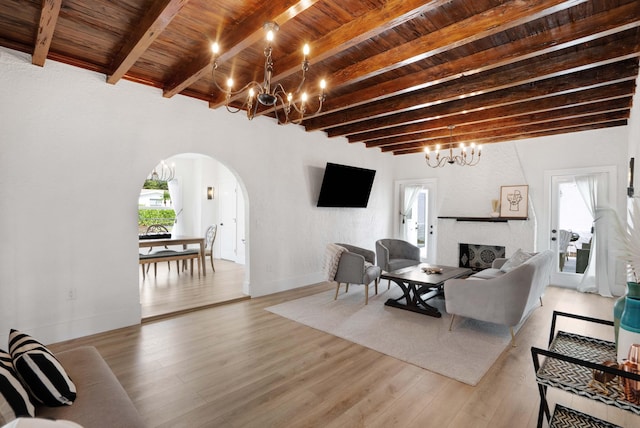 living room featuring light hardwood / wood-style flooring, beamed ceiling, wooden ceiling, and a fireplace