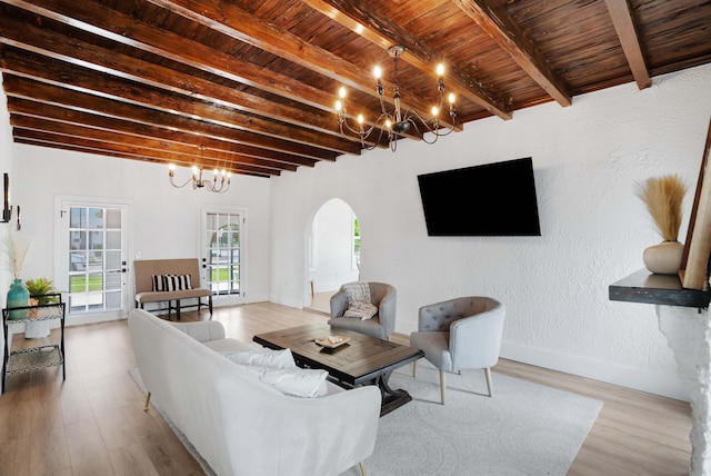 living room featuring beam ceiling, a chandelier, light hardwood / wood-style flooring, and wood ceiling