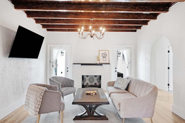 living room with an inviting chandelier, beamed ceiling, and light hardwood / wood-style floors