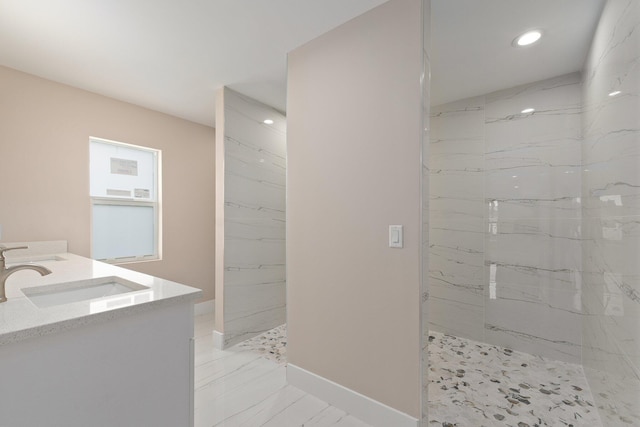 bathroom with tiled shower and vanity