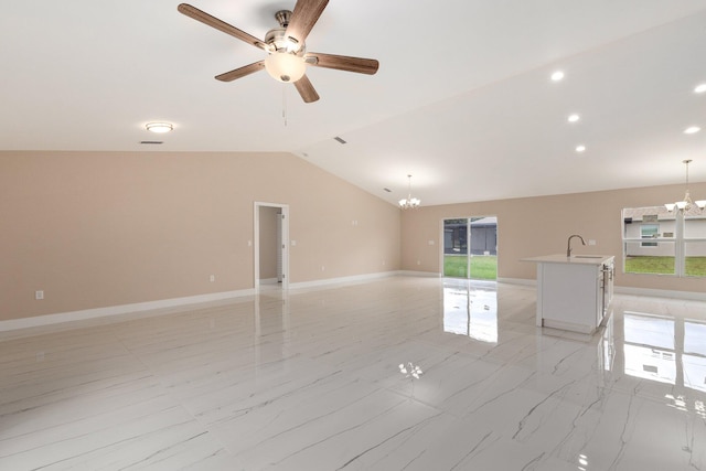 spare room featuring lofted ceiling, a healthy amount of sunlight, sink, and ceiling fan with notable chandelier