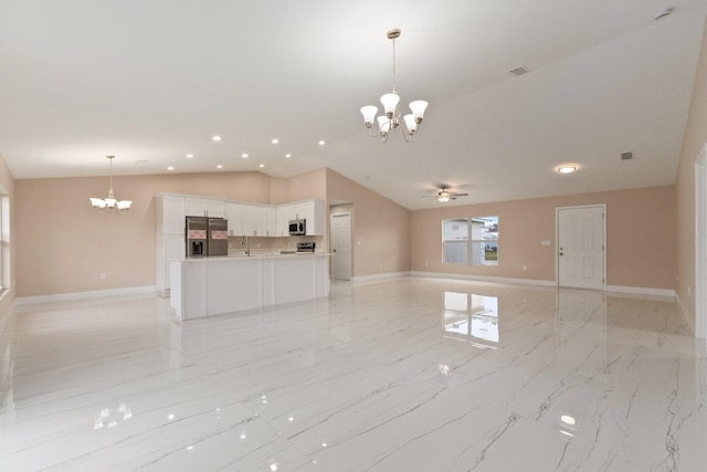 unfurnished living room featuring ceiling fan with notable chandelier, sink, and vaulted ceiling