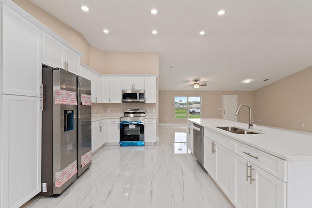 kitchen with appliances with stainless steel finishes, sink, white cabinets, and a center island with sink