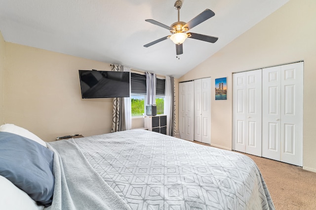 bedroom with light colored carpet, vaulted ceiling, ceiling fan, and multiple closets