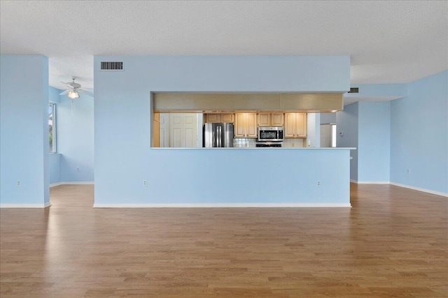 unfurnished living room with ceiling fan, hardwood / wood-style floors, and a textured ceiling