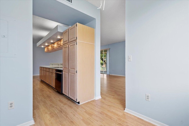 kitchen featuring light brown cabinetry, black dishwasher, sink, light wood-type flooring, and a textured ceiling