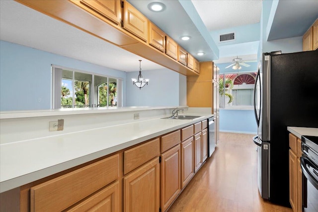 kitchen with sink, hanging light fixtures, light hardwood / wood-style flooring, appliances with stainless steel finishes, and ceiling fan with notable chandelier