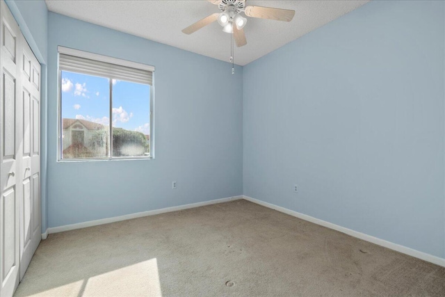 carpeted spare room with ceiling fan