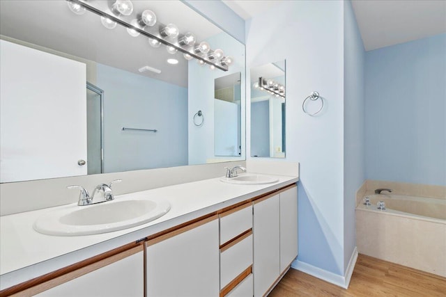 bathroom with vanity, a bath, and wood-type flooring