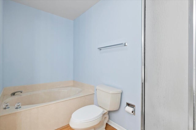 bathroom with a tub to relax in and toilet