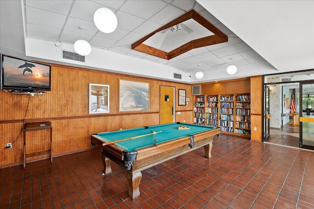 playroom featuring built in shelves, a paneled ceiling, and wooden walls