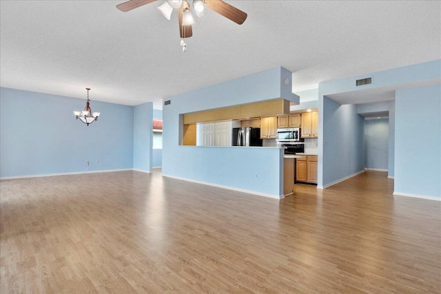 unfurnished living room featuring ceiling fan with notable chandelier, a textured ceiling, and light hardwood / wood-style flooring