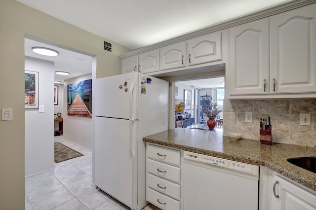 kitchen featuring white appliances, decorative backsplash, dark stone countertops, white cabinets, and light tile patterned flooring