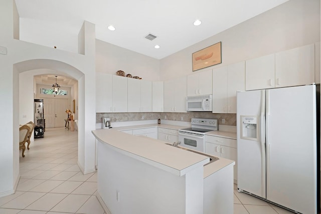 kitchen featuring a center island, light tile patterned floors, white cabinets, white appliances, and tasteful backsplash