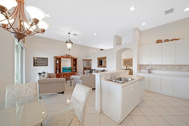 kitchen with white cabinetry, sink, decorative light fixtures, and a kitchen island with sink