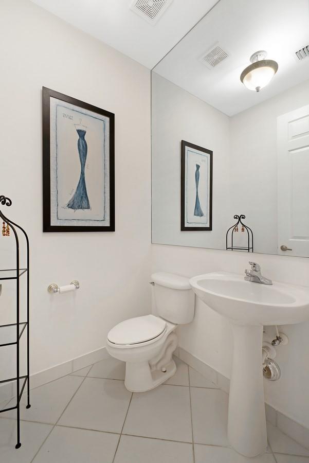 half bathroom with toilet, tile patterned flooring, visible vents, and baseboards