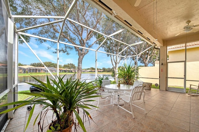 view of patio / terrace with a water view, glass enclosure, and ceiling fan