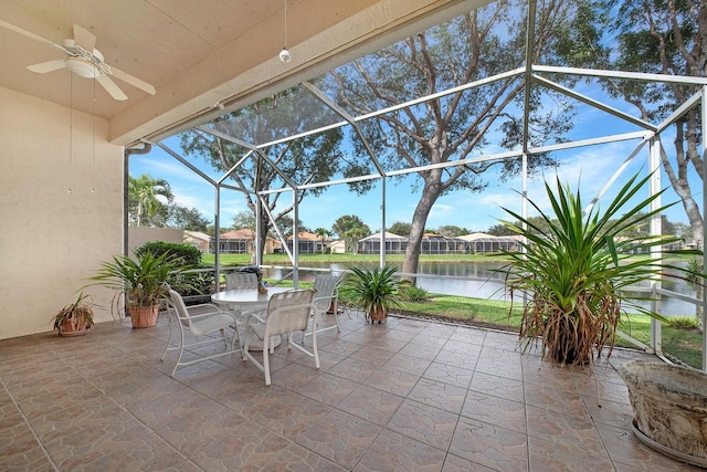 view of patio / terrace with ceiling fan, outdoor dining space, a water view, and a lanai