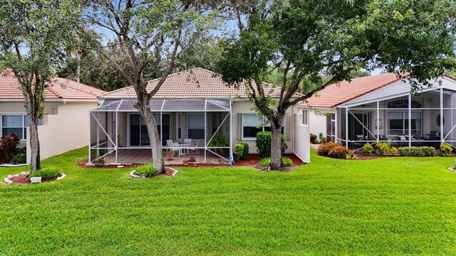 rear view of property with a lanai and a lawn