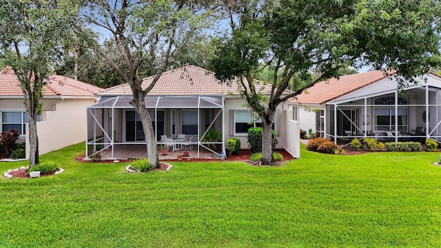 back of house with a tiled roof, a lanai, a yard, a patio area, and stucco siding