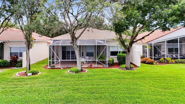 back of house featuring a sunroom, a water view, a lawn, and a lanai