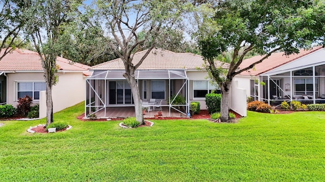 rear view of house featuring a tile roof, a lanai, a yard, a patio area, and stucco siding