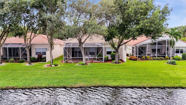 back of property featuring glass enclosure, a tile roof, a water view, a yard, and stucco siding