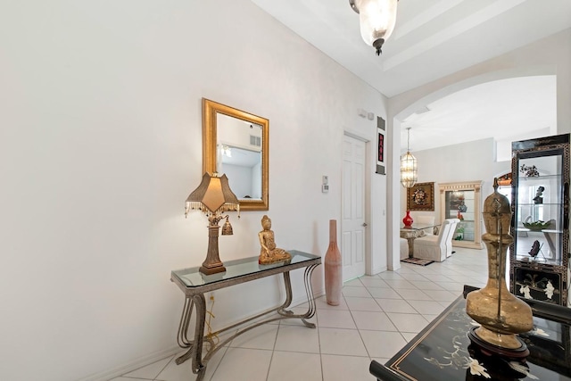 hall featuring arched walkways and light tile patterned flooring