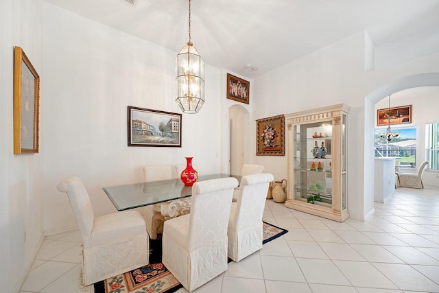 dining area with baseboards, arched walkways, a notable chandelier, and light tile patterned flooring