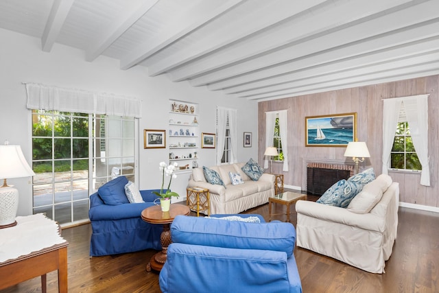 living room featuring a healthy amount of sunlight, a fireplace, beamed ceiling, and dark wood-type flooring