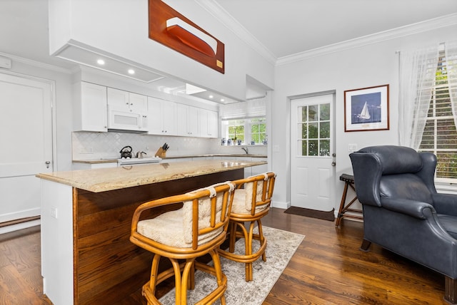 kitchen with white cabinets, a center island, crown molding, and dark wood-type flooring