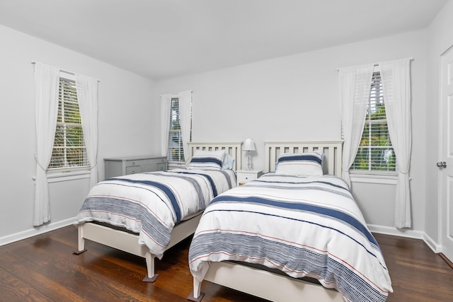 bedroom with multiple windows and dark wood-type flooring