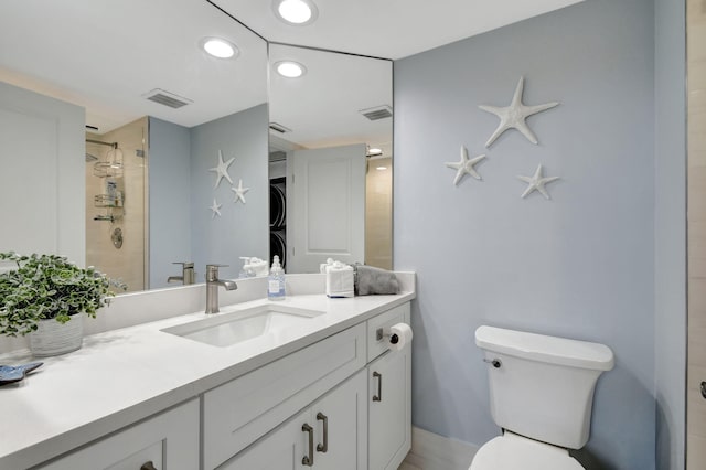 bathroom with toilet, a tile shower, and vanity