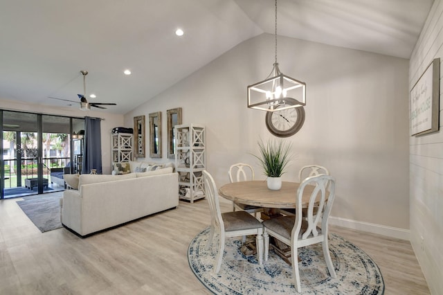 dining space with light hardwood / wood-style flooring, ceiling fan with notable chandelier, and vaulted ceiling